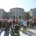 En protest foran Stortinget. Mange av de som er på markeringen holder opp plakater med slagord og Redd Barna-logoen.