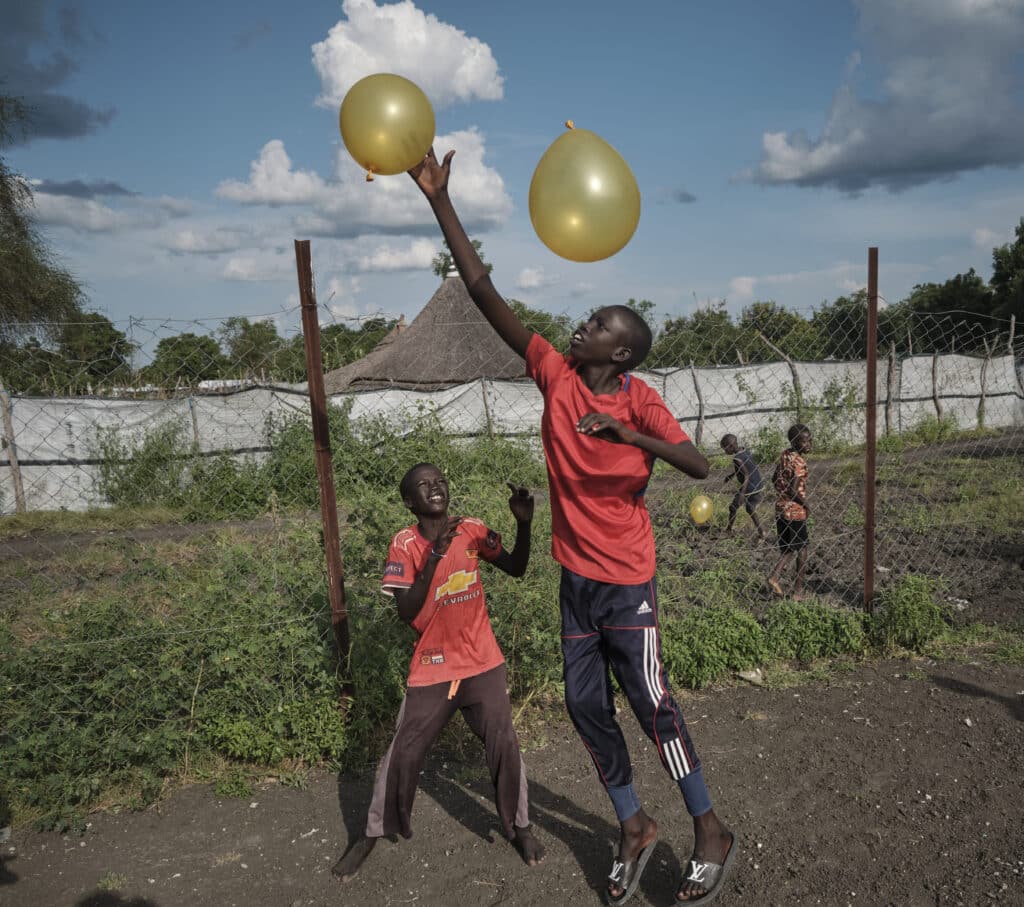 Foto av fire gutter som kaster ballonger i Sør-Sudan. 