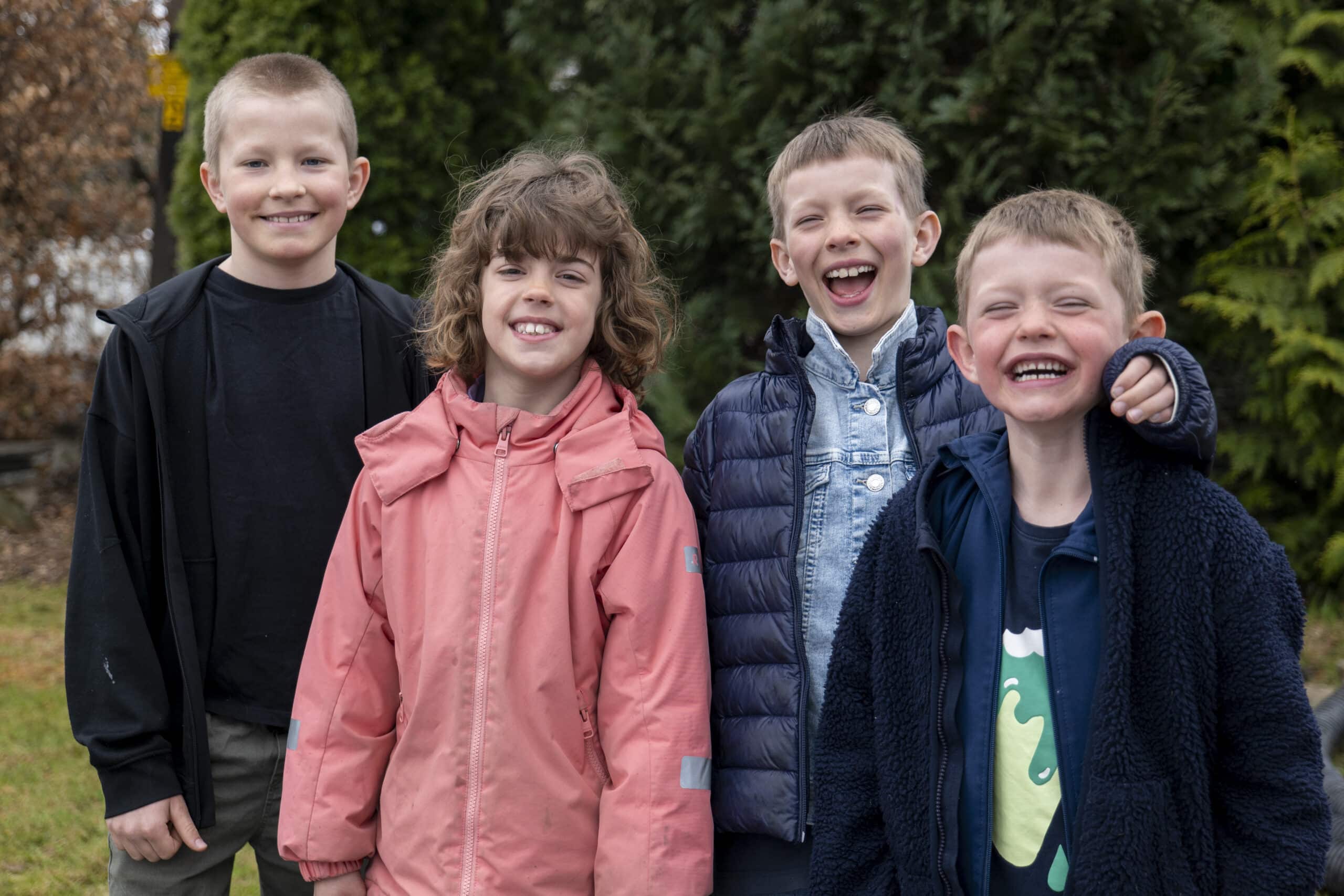 Fire barn står ute i en hage, de ser i kamera og smiler