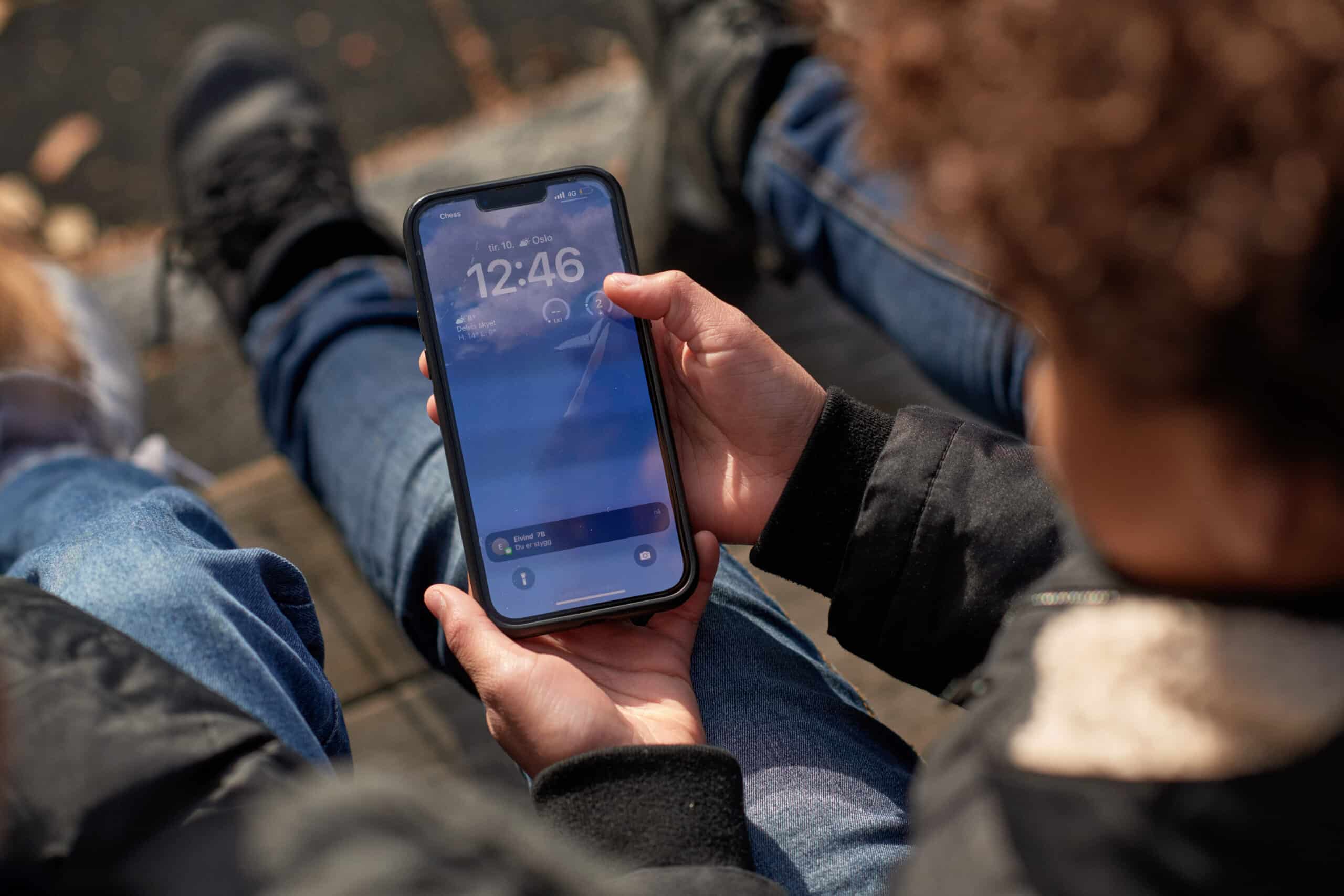 En gutt holder en mobiltelefon, på en melding står det Du er stygg