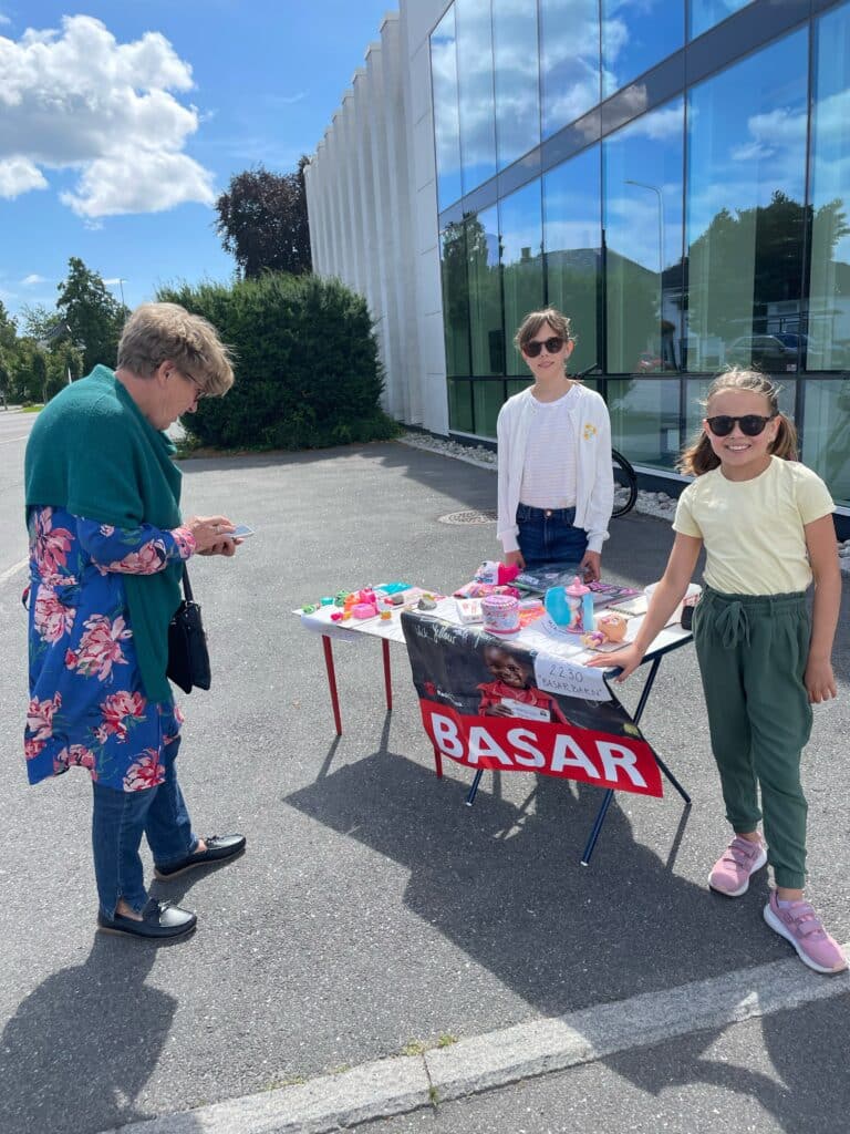 To jenter tar imot betaling på basaren de holder.