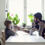En liten gutt og pappaen hans sitter ved et spisebord